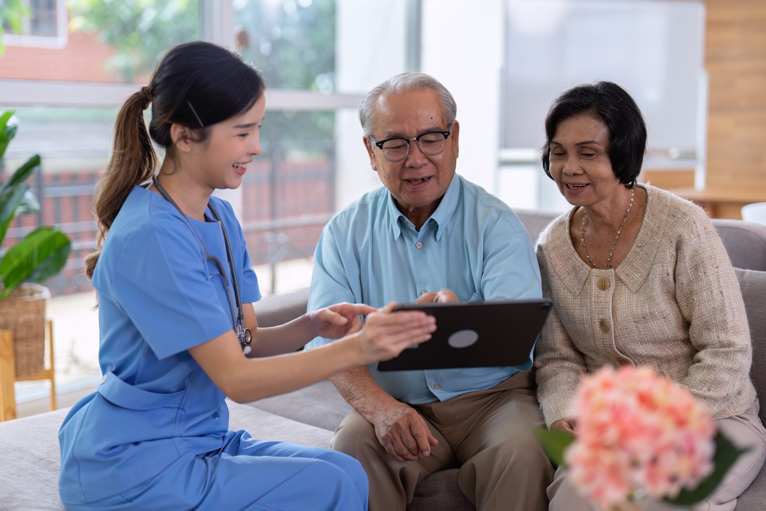 Nurse reviews a care plan on a tablet with an older couple at home.