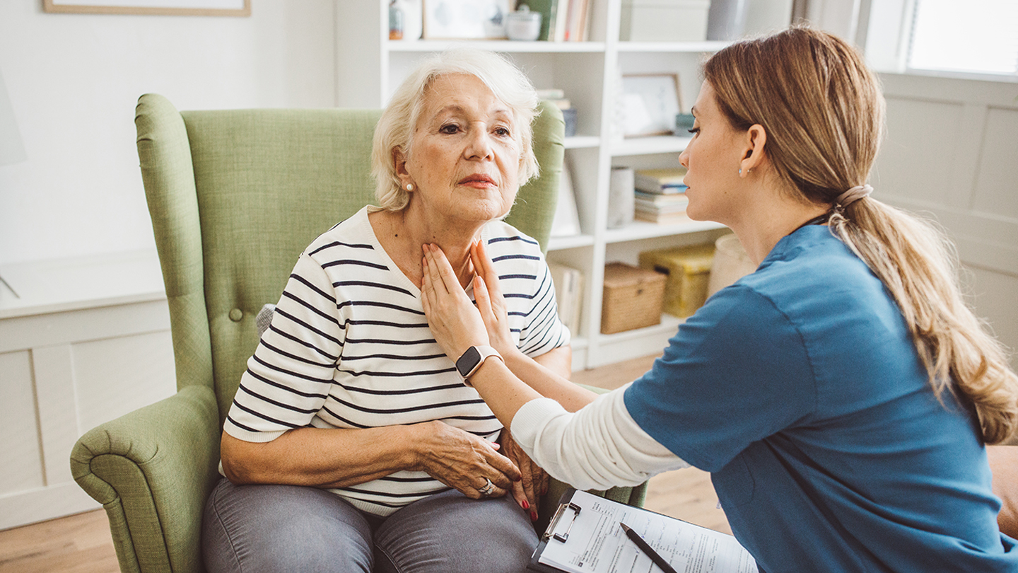 Therapist guides an older adult through gentle recovery exercises during a home visit.