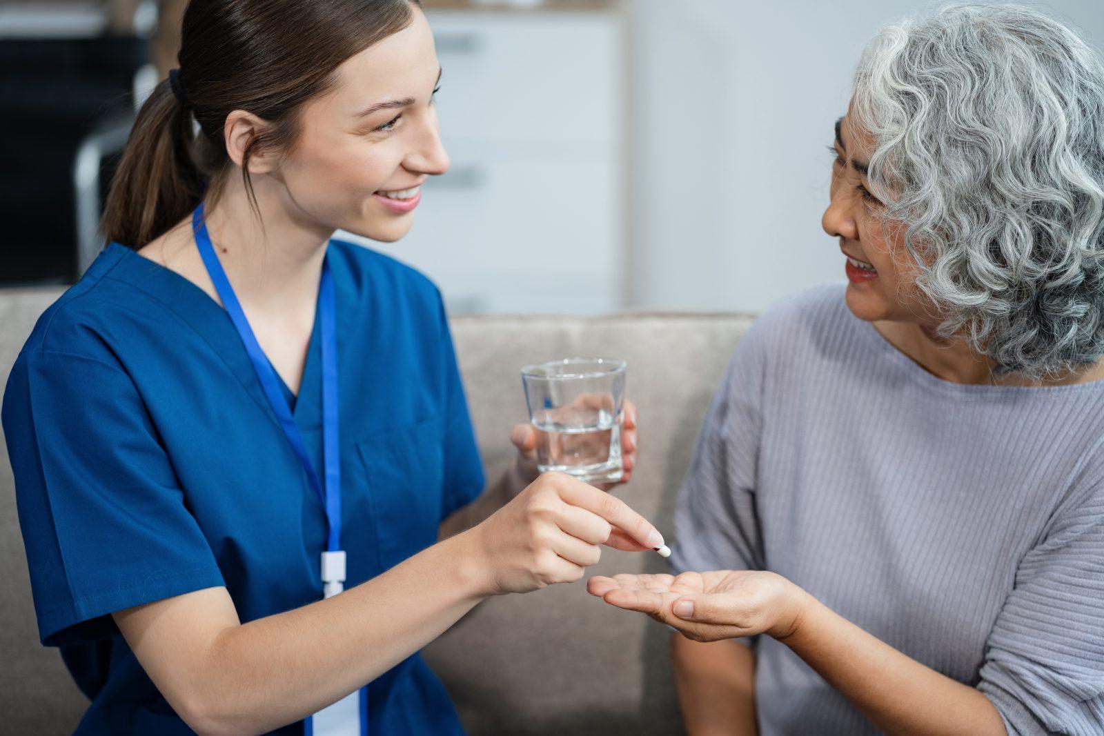 Clinician reviews a medication bottle with an older adult at home.